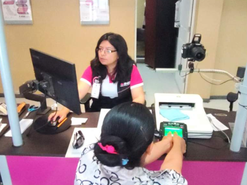 Personal del INE entrega una credencial para votar en un módulo de atención.