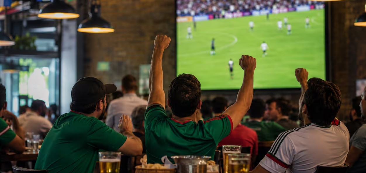Personas viendo un partido de futbol en un restaurante.